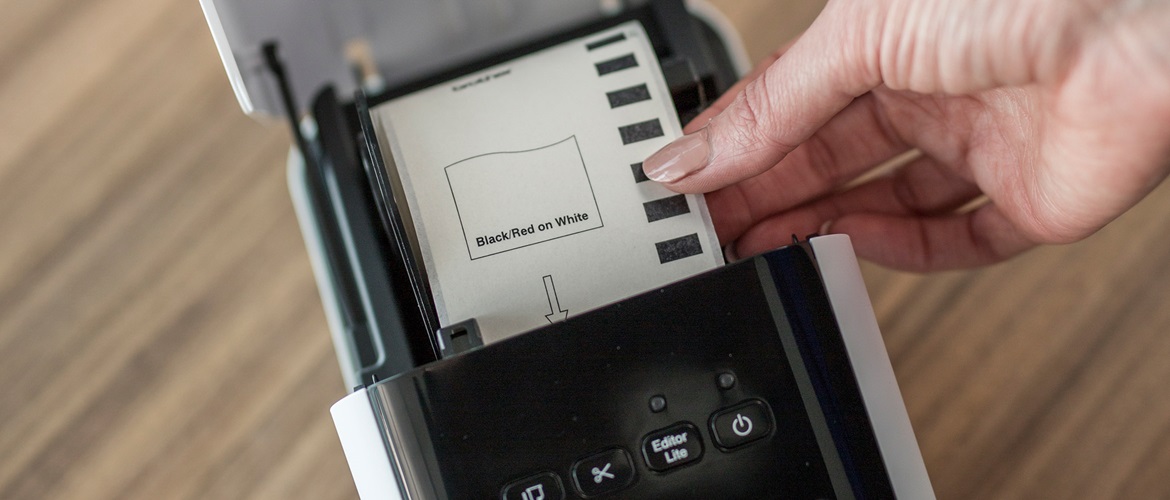 Image of hand fitting a label paper roll in Brother label printer.